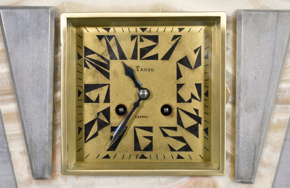 A three-piece French Art Deco clock garniture set featuring a central geometric onyx and marble clock topped with a bronze-finished figure of a female with birds, accompanied by two matching side pedestals. View IX