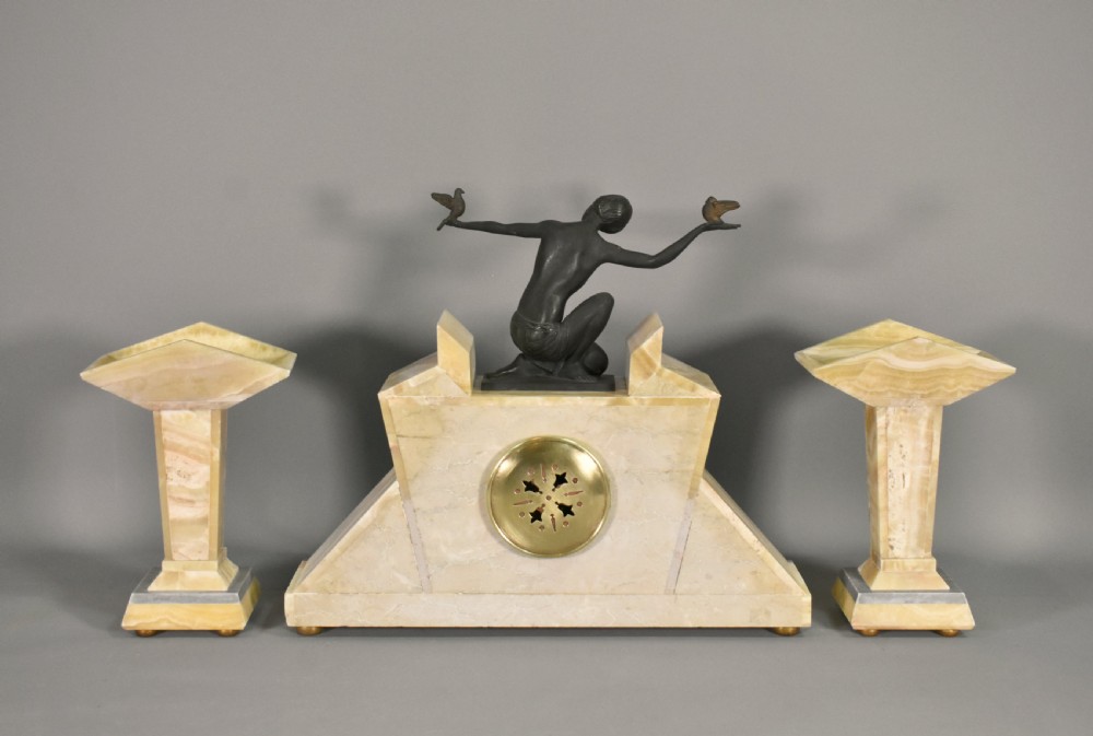 A three-piece French Art Deco clock garniture set featuring a central geometric onyx and marble clock topped with a bronze-finished figure of a female with birds, accompanied by two matching side pedestals. View XIII