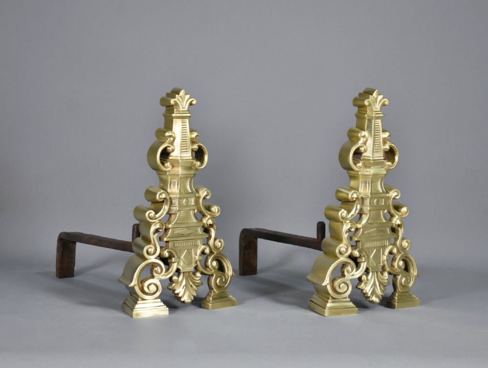 A pair of ornate cast brass French fire dogs featuring scrollwork, acanthus leaf details, and finial tops. View II