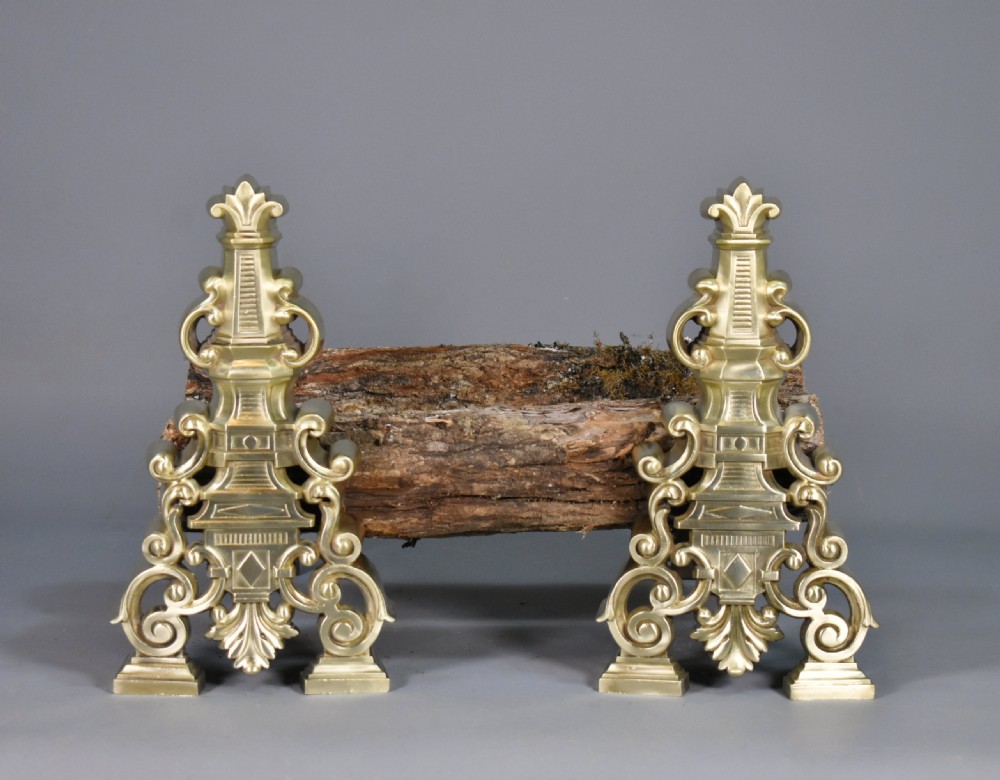 A pair of ornate cast brass French fire dogs featuring scrollwork, acanthus leaf details, and finial tops. View IX