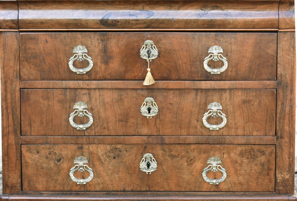 A 19th-century French Louis Philippe walnut commode featuring a rounded top drawer, three lower drawers with brass drop handles, and a plinth base. View V