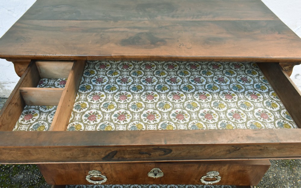 A 19th-century French Louis Philippe walnut commode featuring a rounded top drawer, three lower drawers with brass drop handles, and a plinth base. View XVII