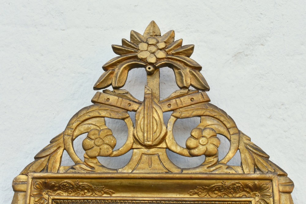 A rectangular French giltwood wall mirror featuring carved floral cresting and a gold leaf frame. View IV