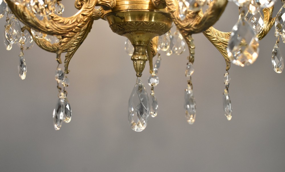 A French gilt brass five-arm chandelier featuring scroll branch arms, faux candle sleeves, and faceted cut glass droplets. View XII