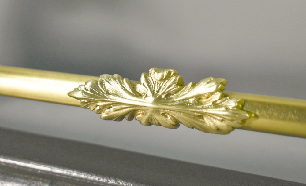 A 19th-century French fireplace fender featuring dark patinated metal greyhound sculptures resting on bases on either side of a polished brass rail with central gold-toned foliate detailing. View VI