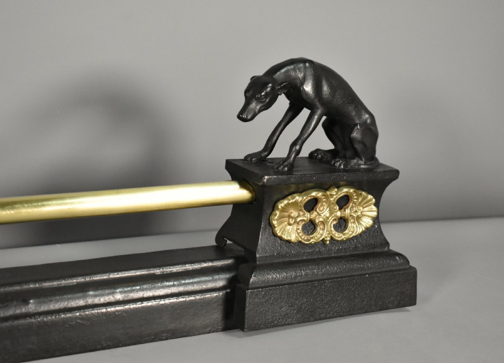 A 19th-century French fireplace fender featuring dark patinated metal greyhound sculptures resting on bases on either side of a polished brass rail with central gold-toned foliate detailing. View VII