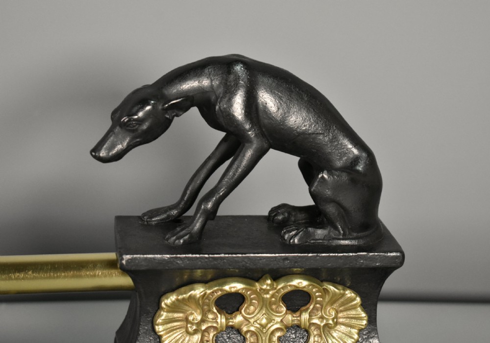 A 19th-century French fireplace fender featuring dark patinated metal greyhound sculptures resting on bases on either side of a polished brass rail with central gold-toned foliate detailing. View VIII