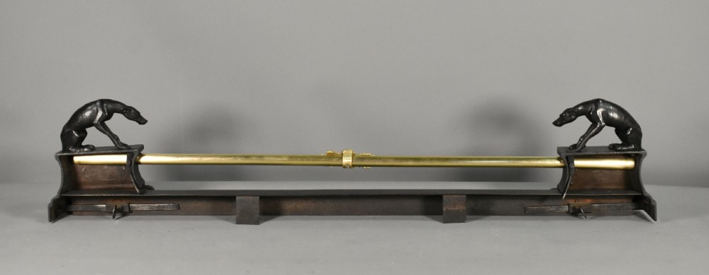 A 19th-century French fireplace fender featuring dark patinated metal greyhound sculptures resting on bases on either side of a polished brass rail with central gold-toned foliate detailing. View XIV