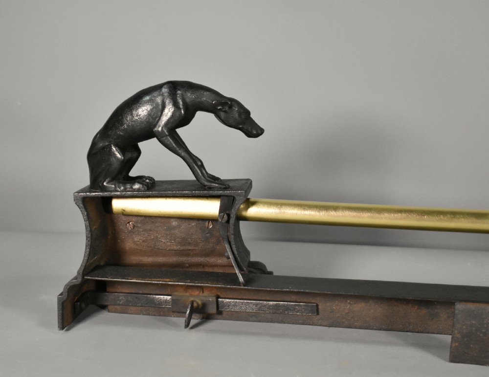 A 19th-century French fireplace fender featuring dark patinated metal greyhound sculptures resting on bases on either side of a polished brass rail with central gold-toned foliate detailing. View XV