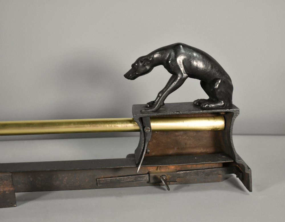 A 19th-century French fireplace fender featuring dark patinated metal greyhound sculptures resting on bases on either side of a polished brass rail with central gold-toned foliate detailing. View XVI