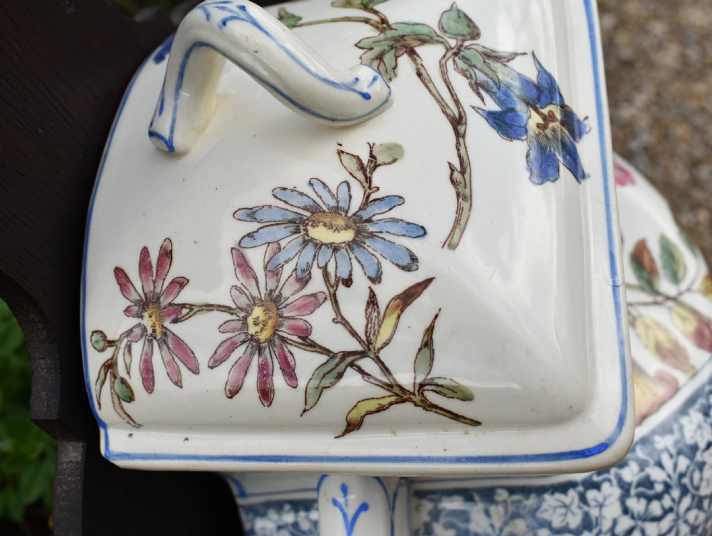 An antique French Art Nouveau cream ceramic wall fountain decorated with botanical floral transfers and a spigot, mounted on a dark carved wooden backboard with a small shelf. View VIII