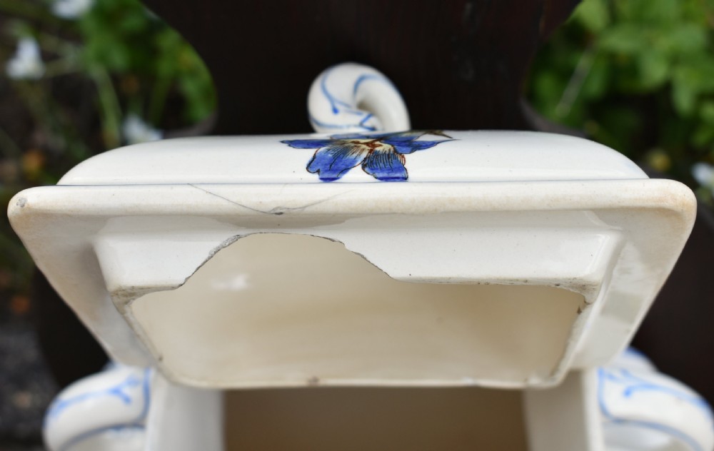 An antique French Art Nouveau cream ceramic wall fountain decorated with botanical floral transfers and a spigot, mounted on a dark carved wooden backboard with a small shelf. View XVII