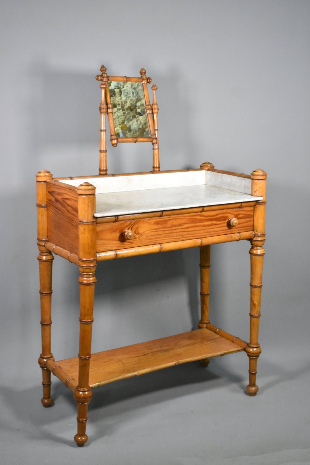 An antique French Napoleon III style washstand with a turned pine faux bamboo frame, marble top, lower shelf, and attached tilting mirror. View II