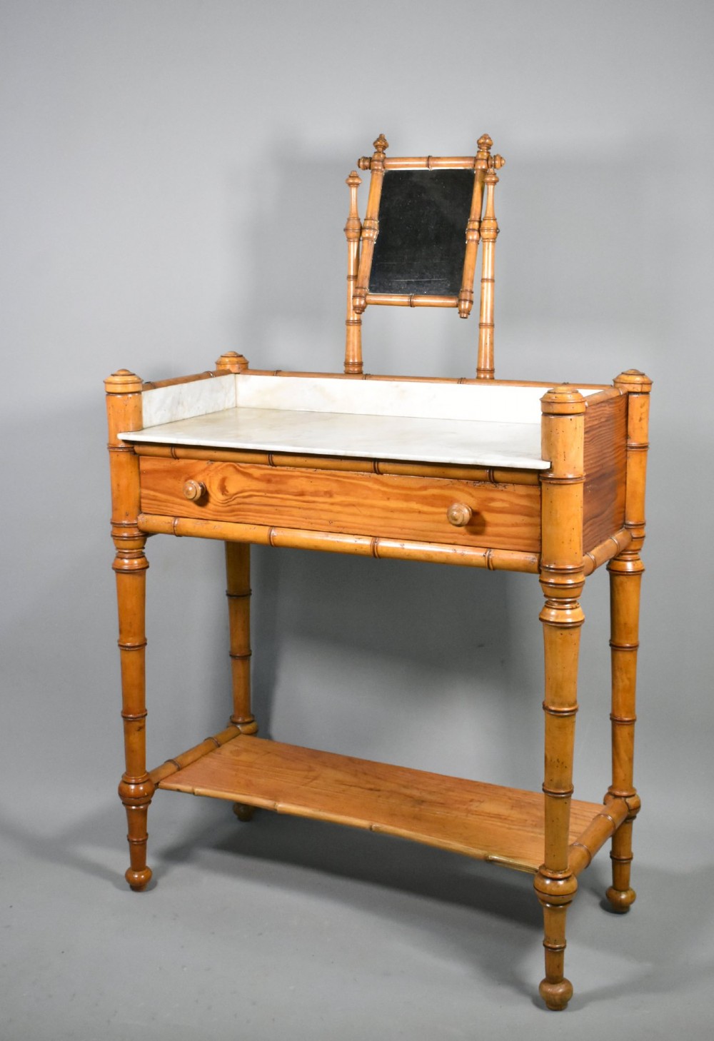 An antique French Napoleon III style washstand with a turned pine faux bamboo frame, marble top, lower shelf, and attached tilting mirror. View III
