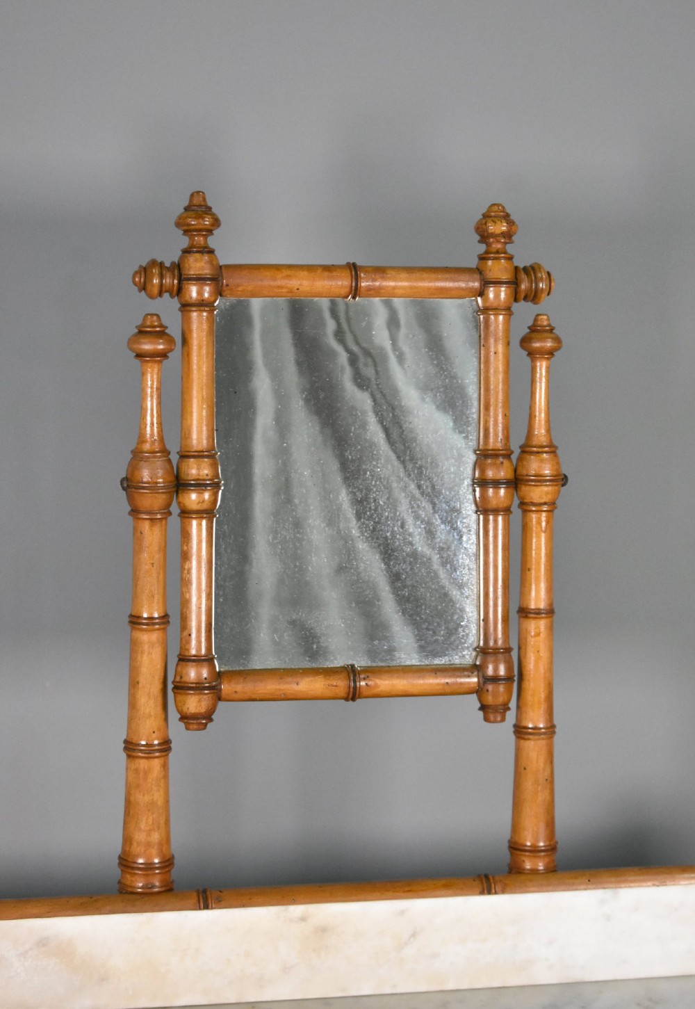 An antique French Napoleon III style washstand with a turned pine faux bamboo frame, marble top, lower shelf, and attached tilting mirror. View VI