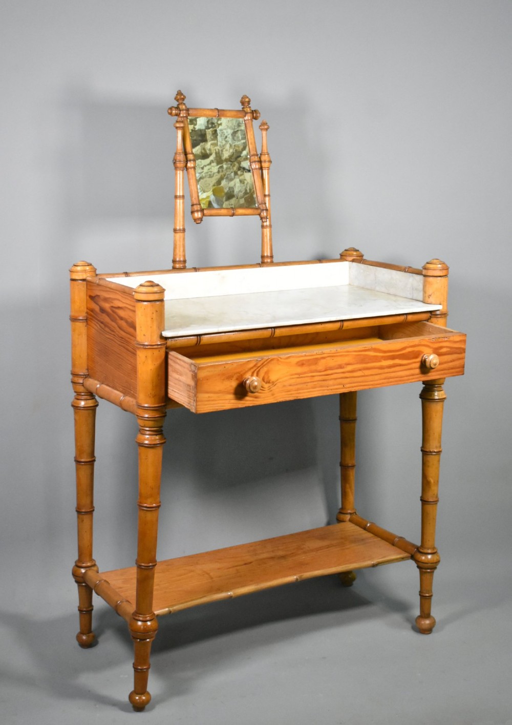 An antique French Napoleon III style washstand with a turned pine faux bamboo frame, marble top, lower shelf, and attached tilting mirror. View X