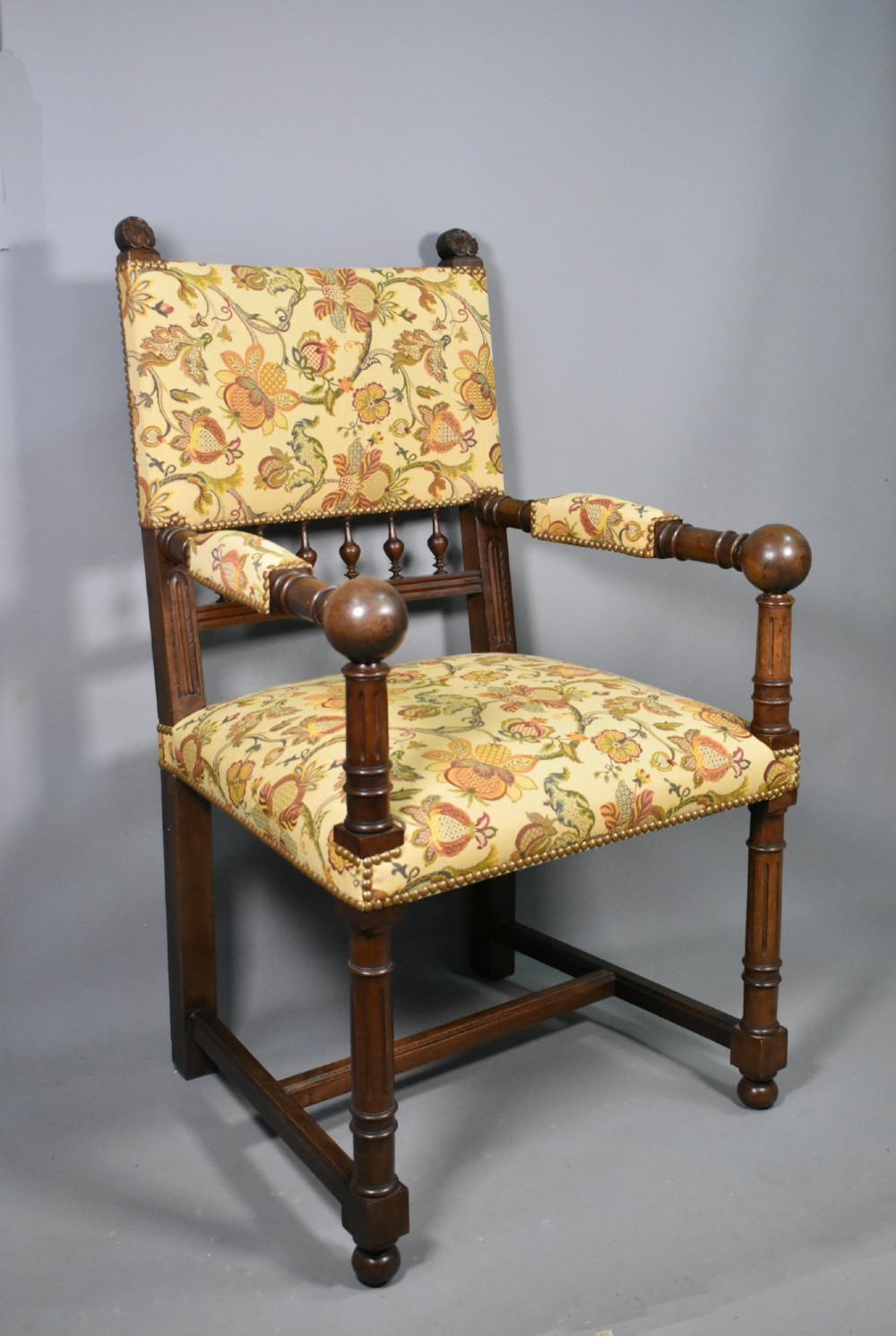 A French Renaissance Revival walnut armchair featuring yellow floral upholstery, brass stud trim, turned legs, spherical armrests, and a spindle gallery backrest. View II