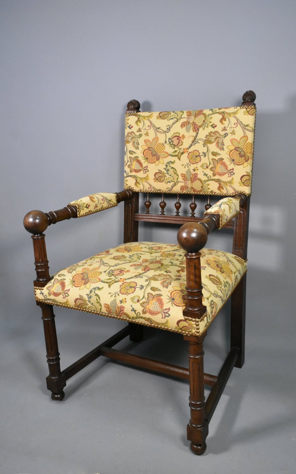 A French Renaissance Revival walnut armchair featuring yellow floral upholstery, brass stud trim, turned legs, spherical armrests, and a spindle gallery backrest. View III