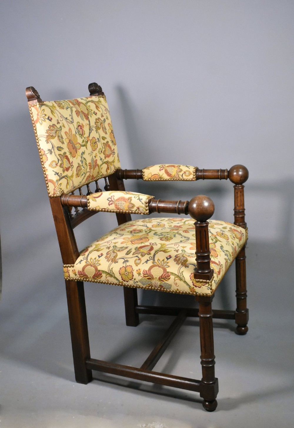 A French Renaissance Revival walnut armchair featuring yellow floral upholstery, brass stud trim, turned legs, spherical armrests, and a spindle gallery backrest. View IV