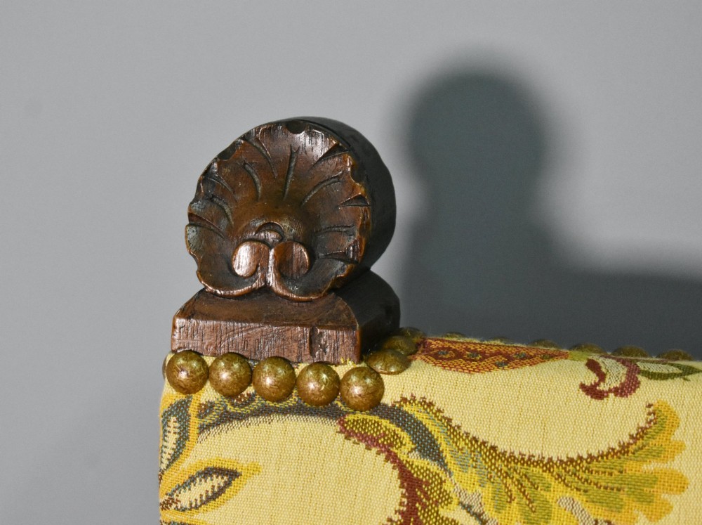 A French Renaissance Revival walnut armchair featuring yellow floral upholstery, brass stud trim, turned legs, spherical armrests, and a spindle gallery backrest. View VII