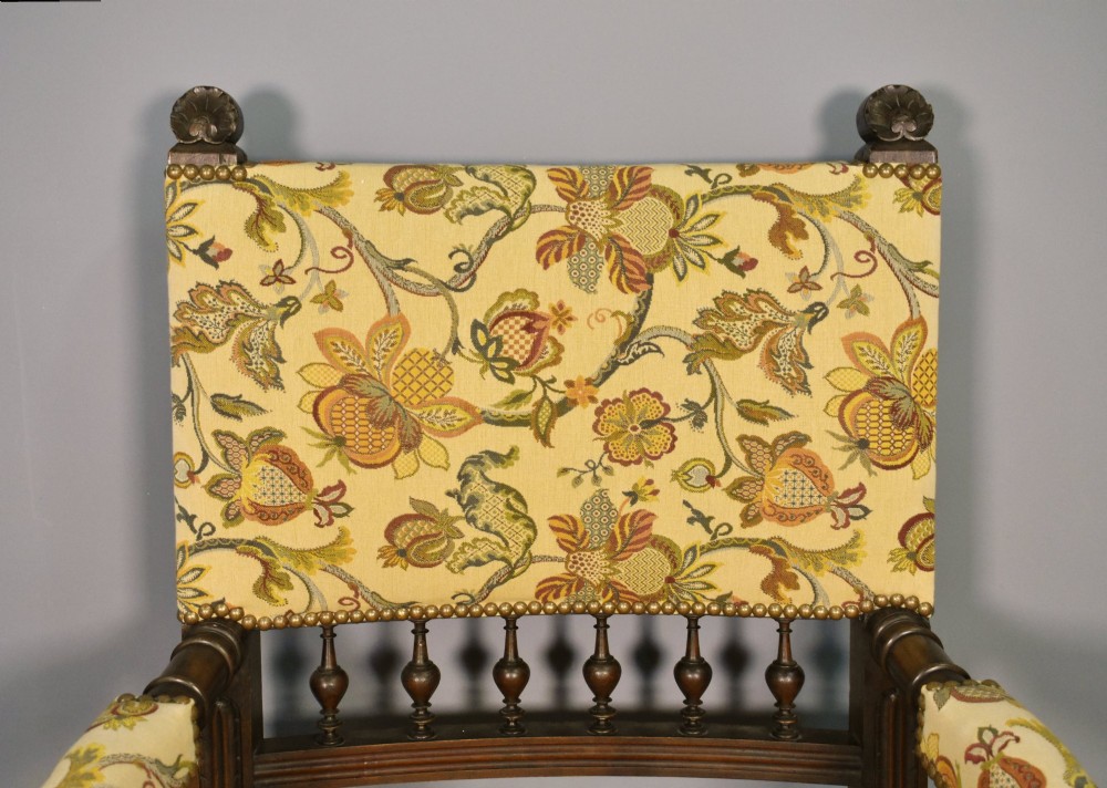 A French Renaissance Revival walnut armchair featuring yellow floral upholstery, brass stud trim, turned legs, spherical armrests, and a spindle gallery backrest. View IX