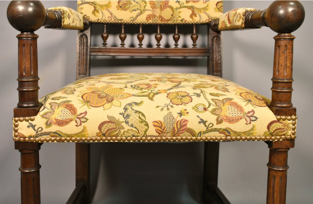 A French Renaissance Revival walnut armchair featuring yellow floral upholstery, brass stud trim, turned legs, spherical armrests, and a spindle gallery backrest. View XI
