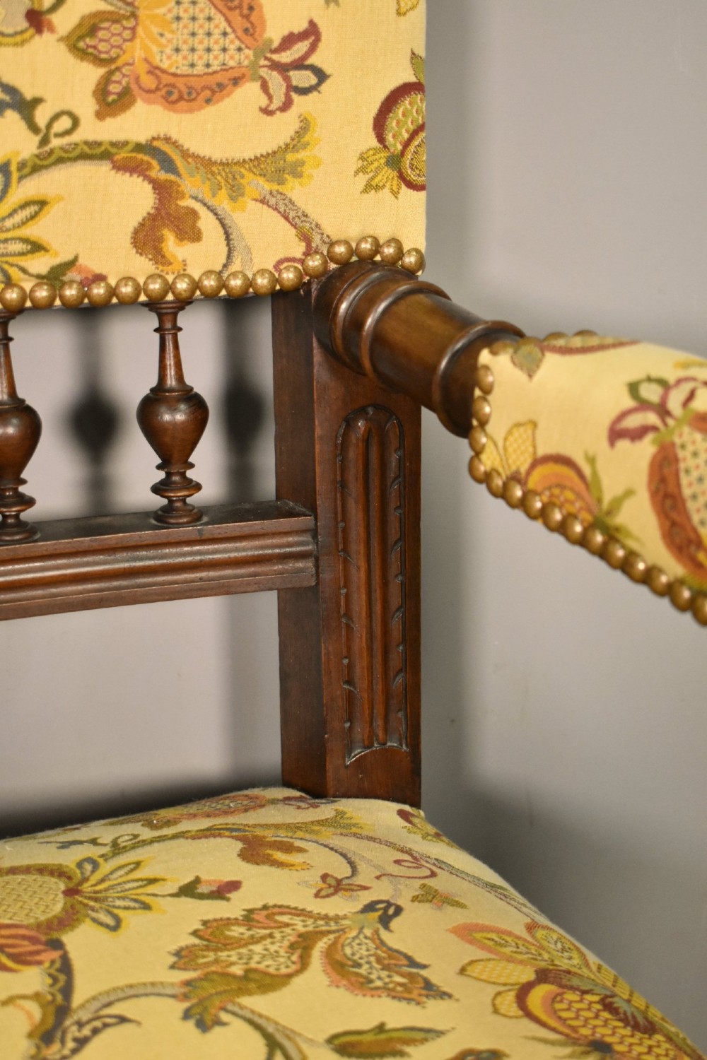 A French Renaissance Revival walnut armchair featuring yellow floral upholstery, brass stud trim, turned legs, spherical armrests, and a spindle gallery backrest. View XIII
