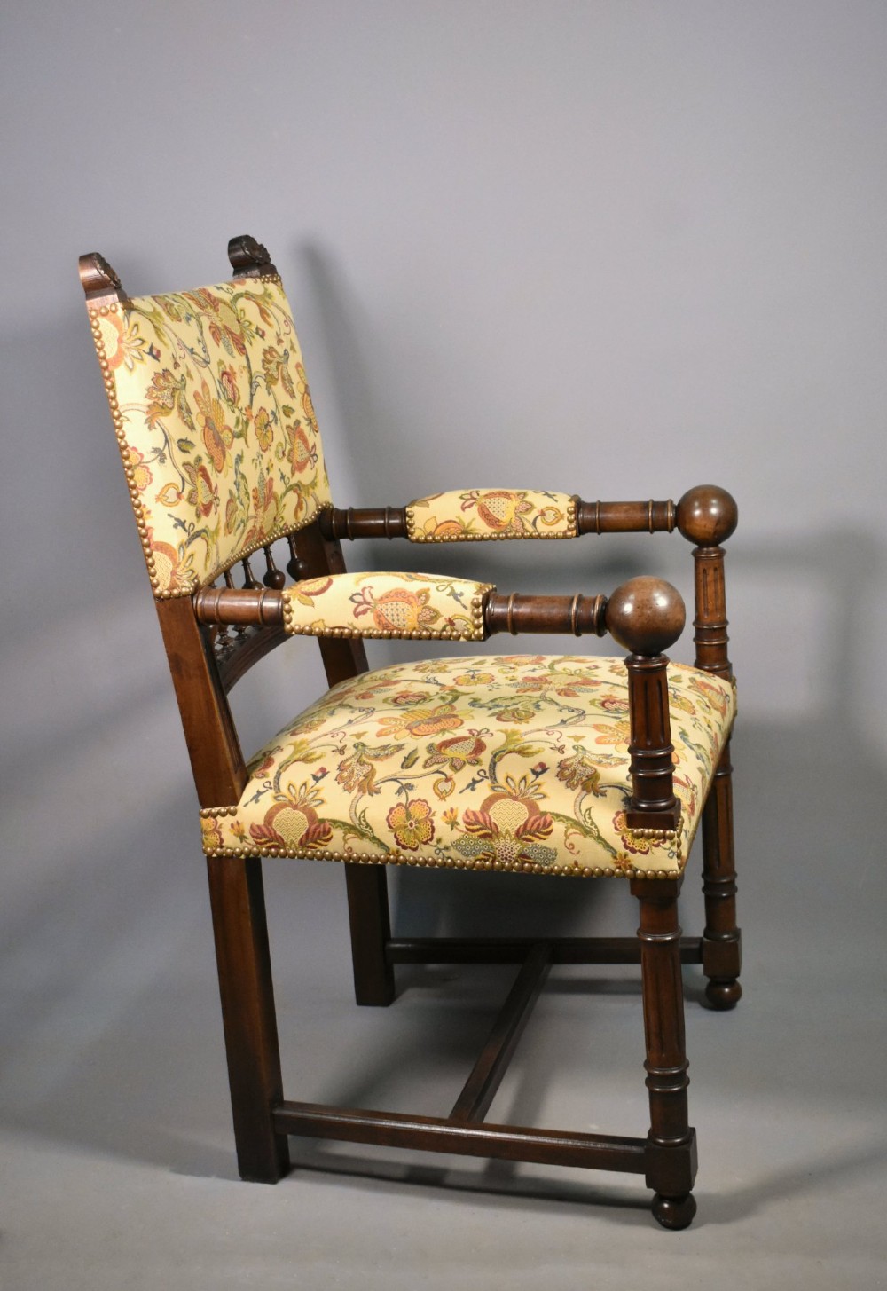 A French Renaissance Revival walnut armchair featuring yellow floral upholstery, brass stud trim, turned legs, spherical armrests, and a spindle gallery backrest. View XIV