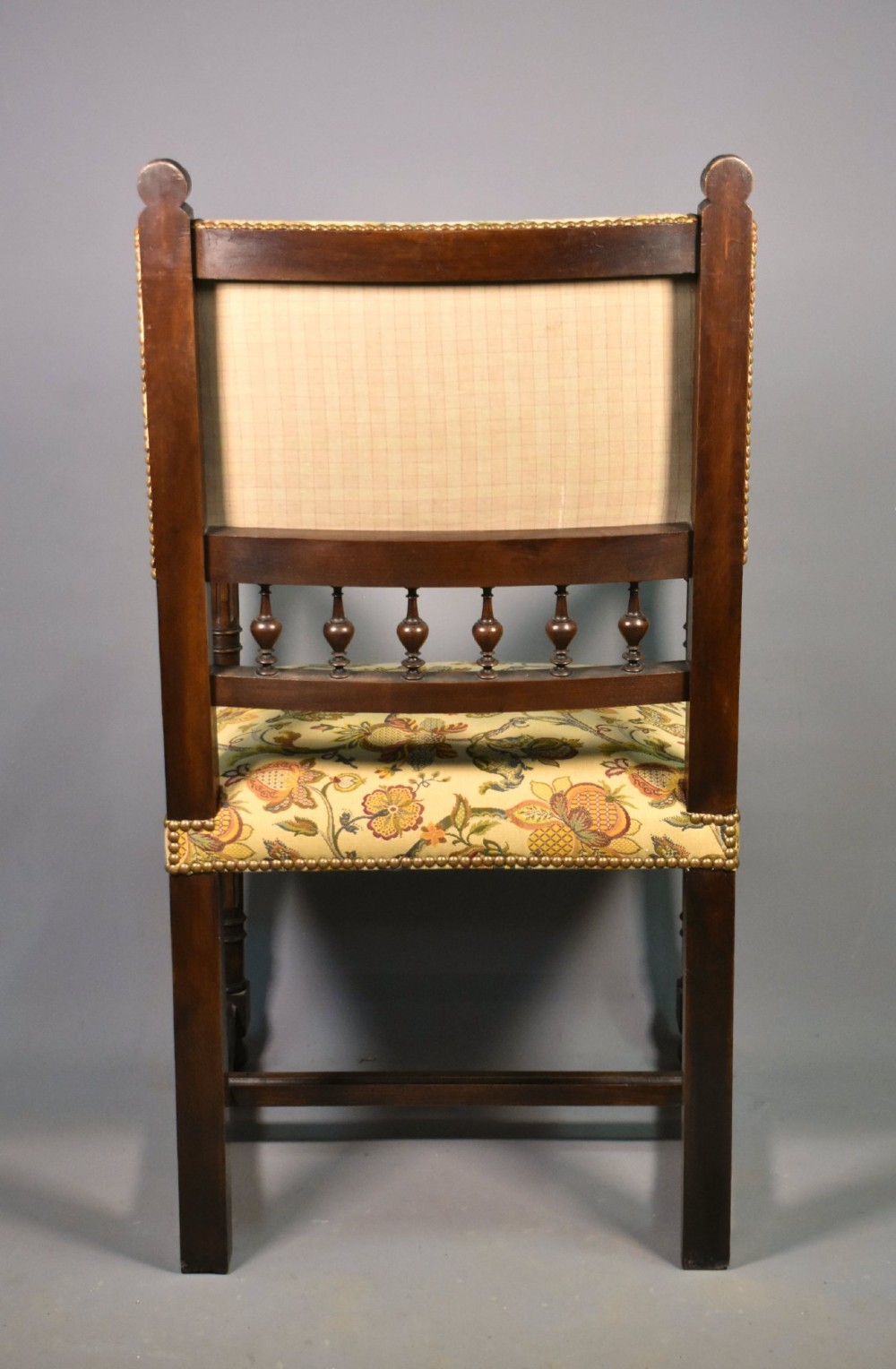 A French Renaissance Revival walnut armchair featuring yellow floral upholstery, brass stud trim, turned legs, spherical armrests, and a spindle gallery backrest. View XV