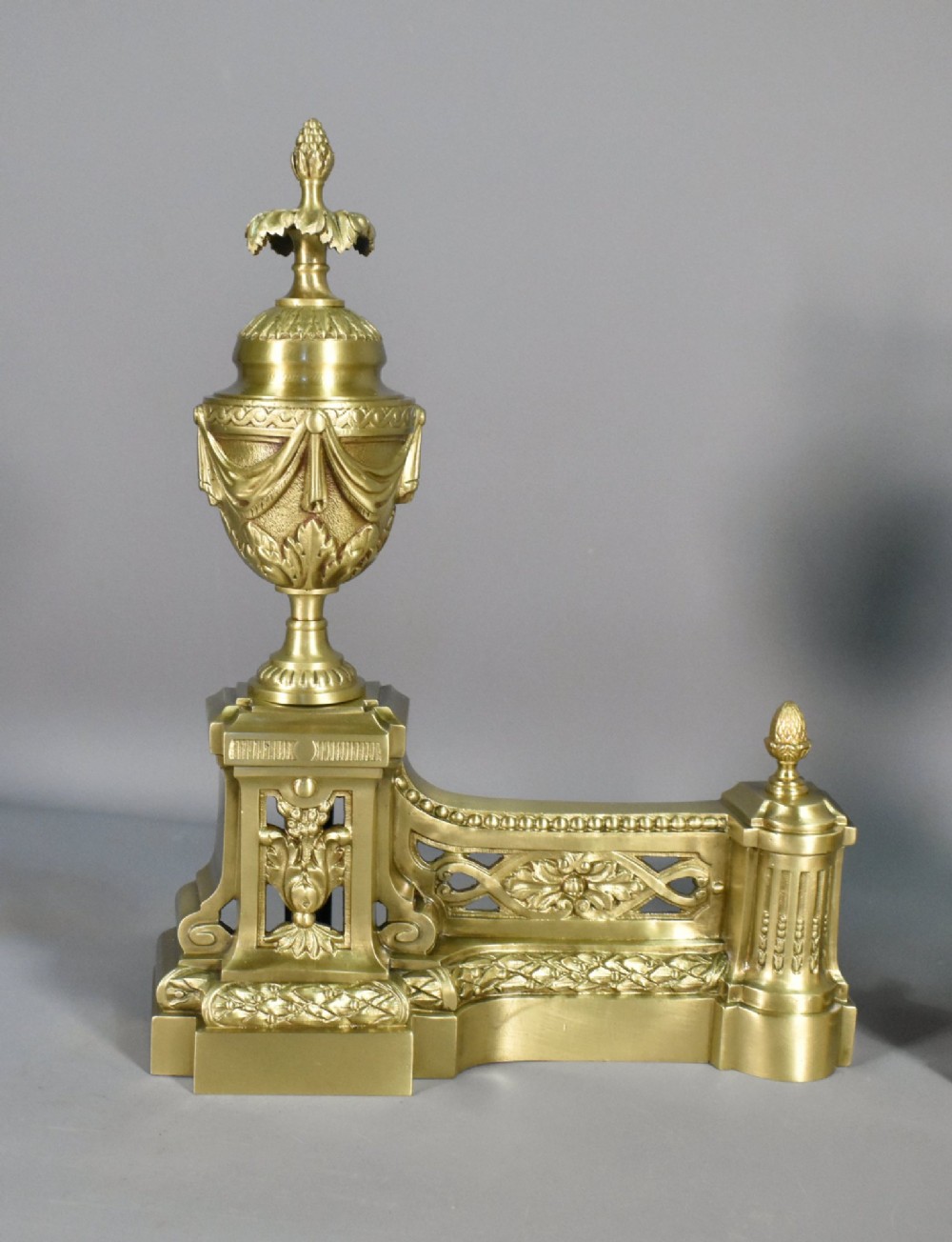 A pair of nineteenth-century French bronze fire dogs featuring carved urn finials, draped swags, and openwork bases. View IV