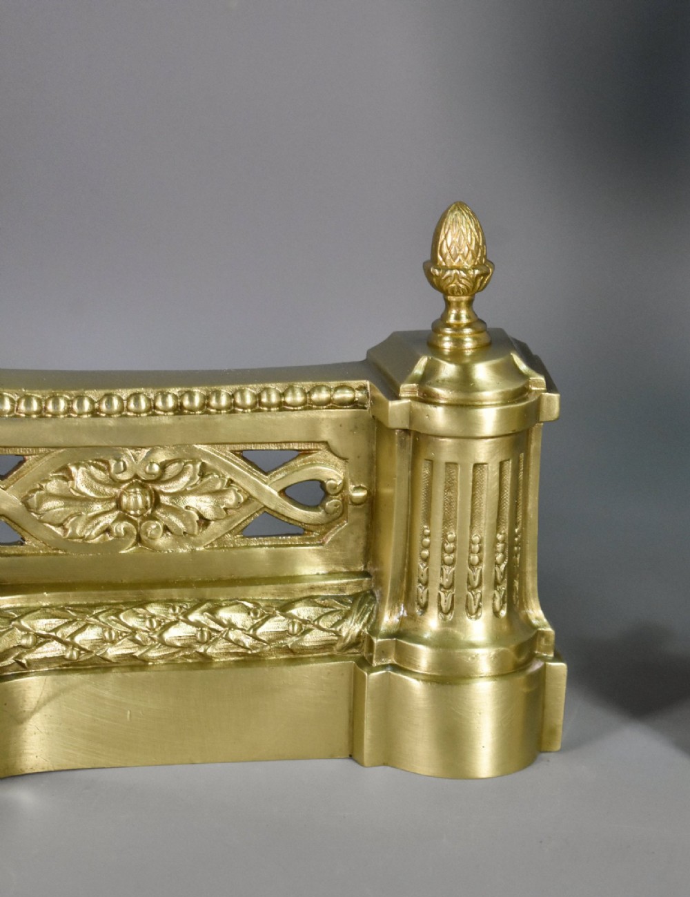 A pair of nineteenth-century French bronze fire dogs featuring carved urn finials, draped swags, and openwork bases. View V