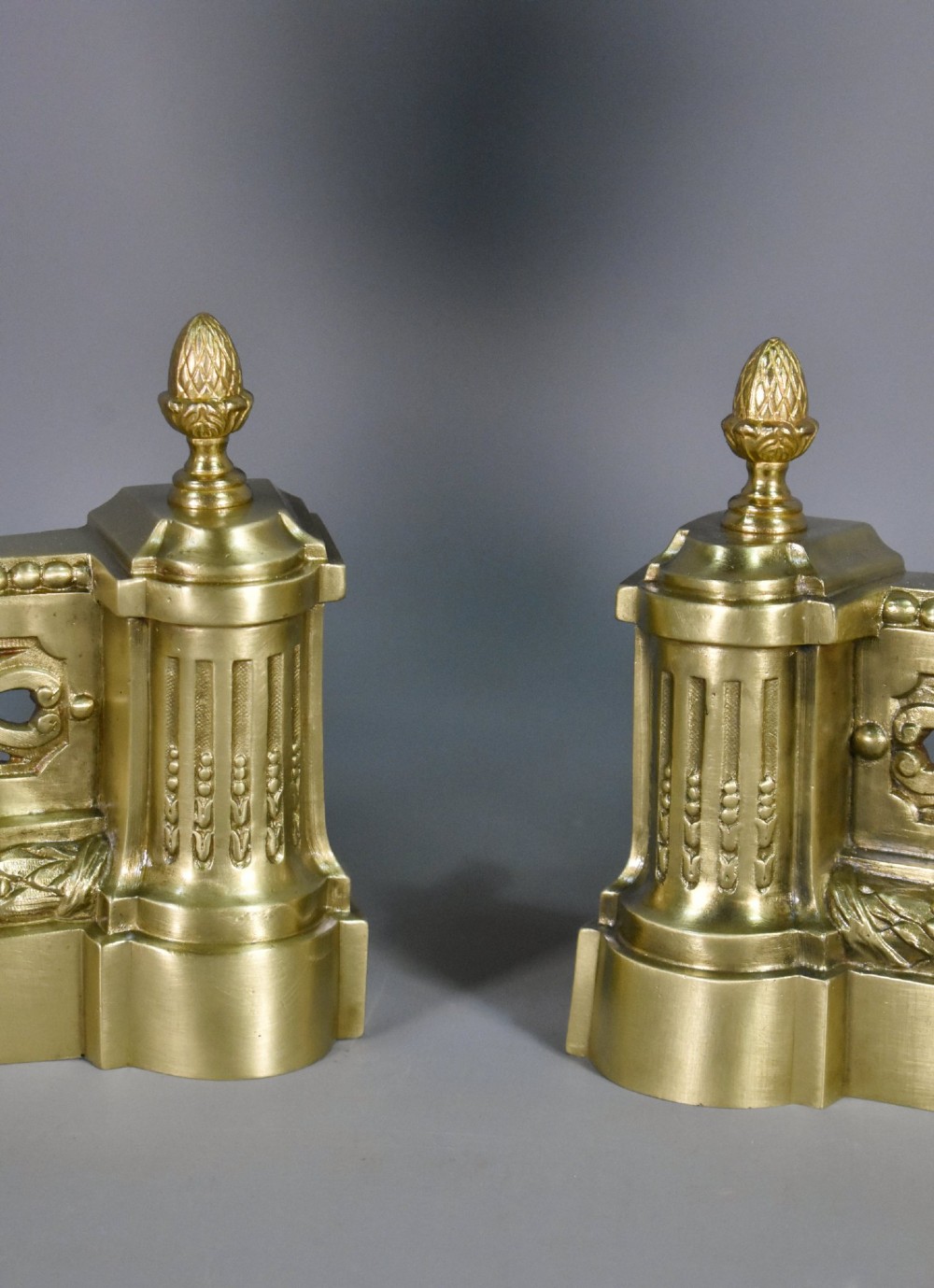 A pair of nineteenth-century French bronze fire dogs featuring carved urn finials, draped swags, and openwork bases. View VI