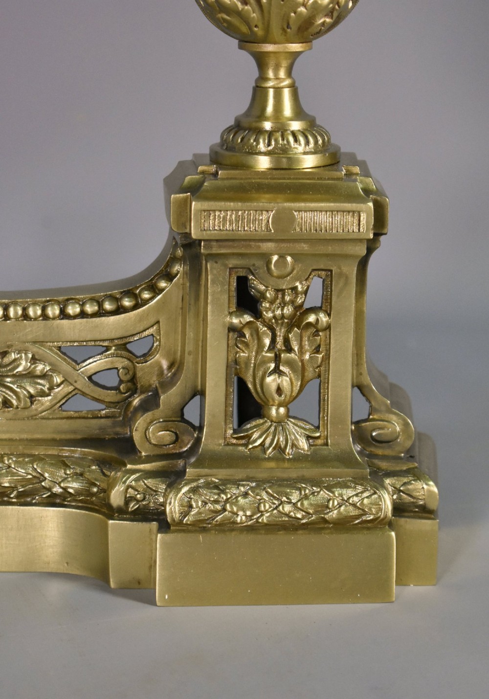 A pair of nineteenth-century French bronze fire dogs featuring carved urn finials, draped swags, and openwork bases. View X