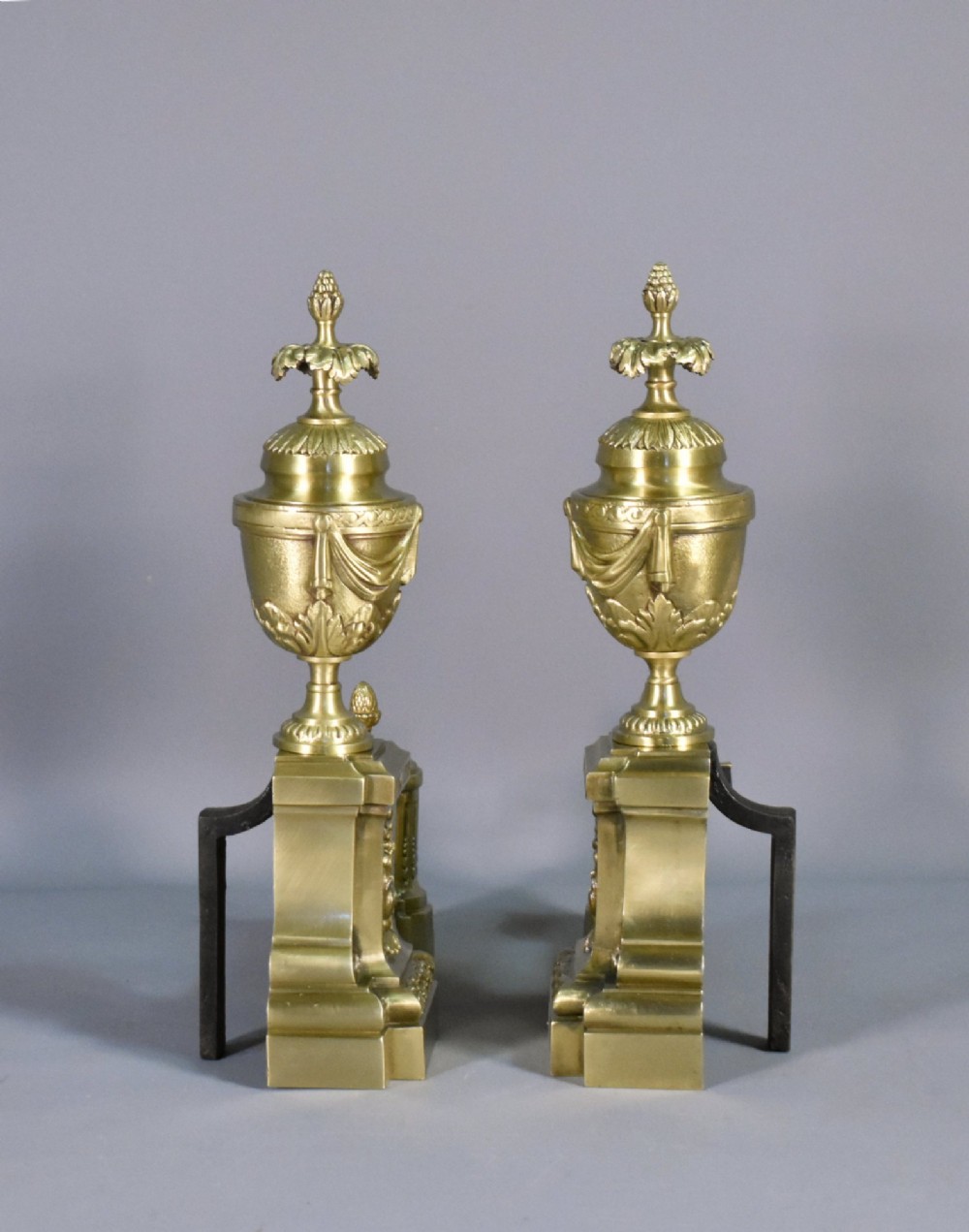 A pair of nineteenth-century French bronze fire dogs featuring carved urn finials, draped swags, and openwork bases. View XII