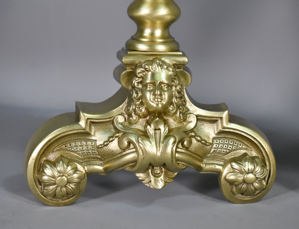 A pair of cast bronze Louis XIV style firedogs featuring baluster shafts, flame finials, and scrolled bases with relief mask carvings. View VI