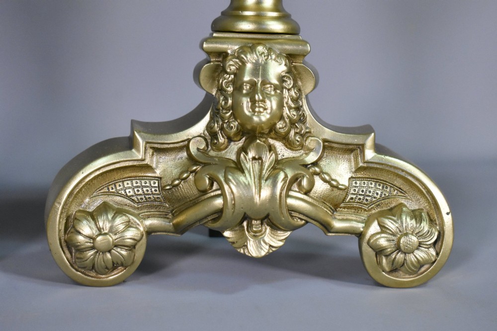 A pair of cast bronze Louis XIV style firedogs featuring baluster shafts, flame finials, and scrolled bases with relief mask carvings. View IX