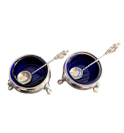 fig 1. A pair of Victorian sterling silver open salt cellars featuring beaded rims, cabriole legs, cobalt blue glass liners, and matching silver salt spoons.