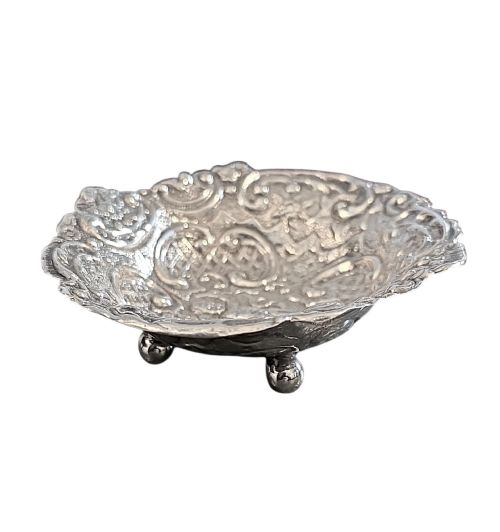 fig 1. An antique oval sterling silver bonbon dish featuring embossed scrollwork, lattice detailing, a central cherub figure, and spherical ball feet.