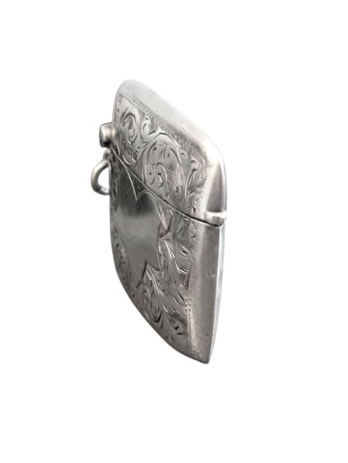 fig 2. A small rectangular sterling silver vesta case with hand-engraved scrollwork, a central vacant shield cartouche, and a side suspension ring.
