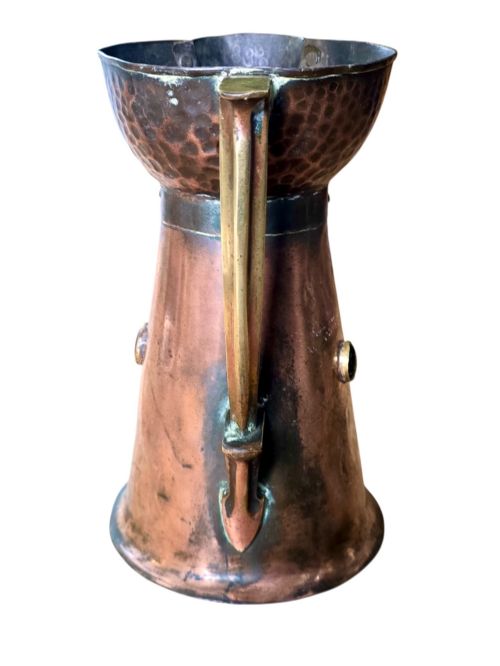fig 1. An antique Arts and Crafts copper jug featuring a planished finish, riveted collar, brass handle, and inset coloured cabochons.