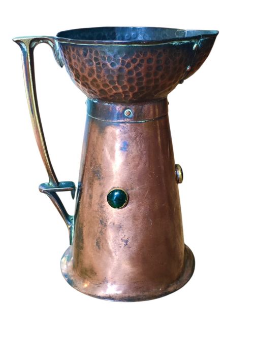 fig 2. An antique Arts and Crafts copper jug featuring a planished finish, riveted collar, brass handle, and inset coloured cabochons.