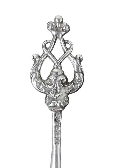 fig 1. A set of eight sterling silver hors doeuvre skewers arranged in a fan shape, featuring ornate openwork scrollwork handles and tapered pins.