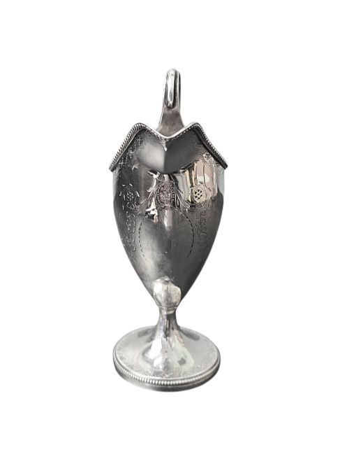fig 1. A George III sterling silver helmet-shaped cream jug with bright-cut floral engraving, a beaded rim, a high loop handle, and a circular pedestal foot.