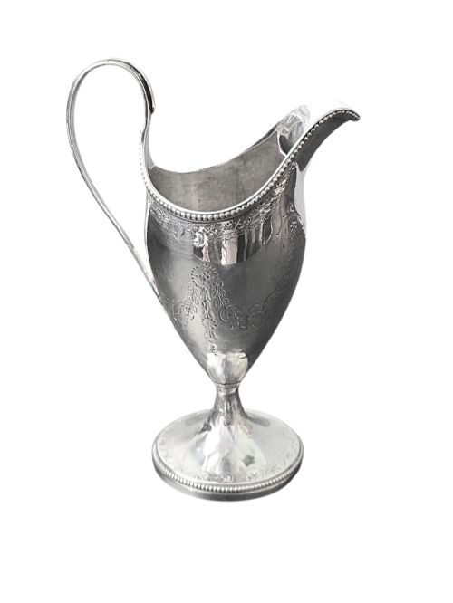 fig 2. A George III sterling silver helmet-shaped cream jug with bright-cut floral engraving, a beaded rim, a high loop handle, and a circular pedestal foot.