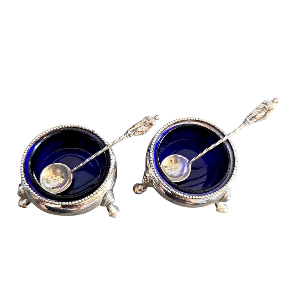 A pair of Victorian sterling silver open salt cellars featuring beaded rims, cabriole legs, cobalt blue glass liners, and matching silver salt spoons. View II