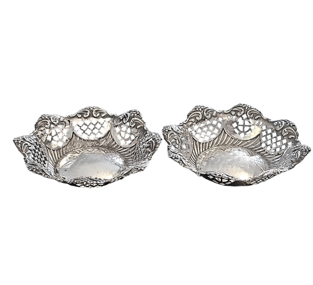 A pair of late Victorian sterling silver bonbon dishes with pierced lattice rims and scrolled edges.