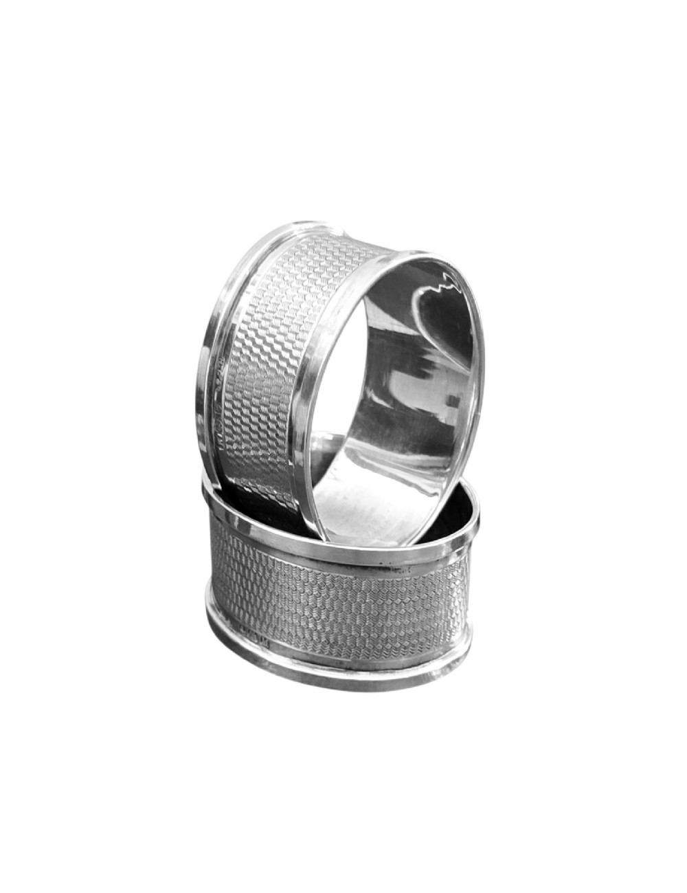 A pair of oval sterling silver napkin rings featuring an engine-turned textured band and plain polished edges.