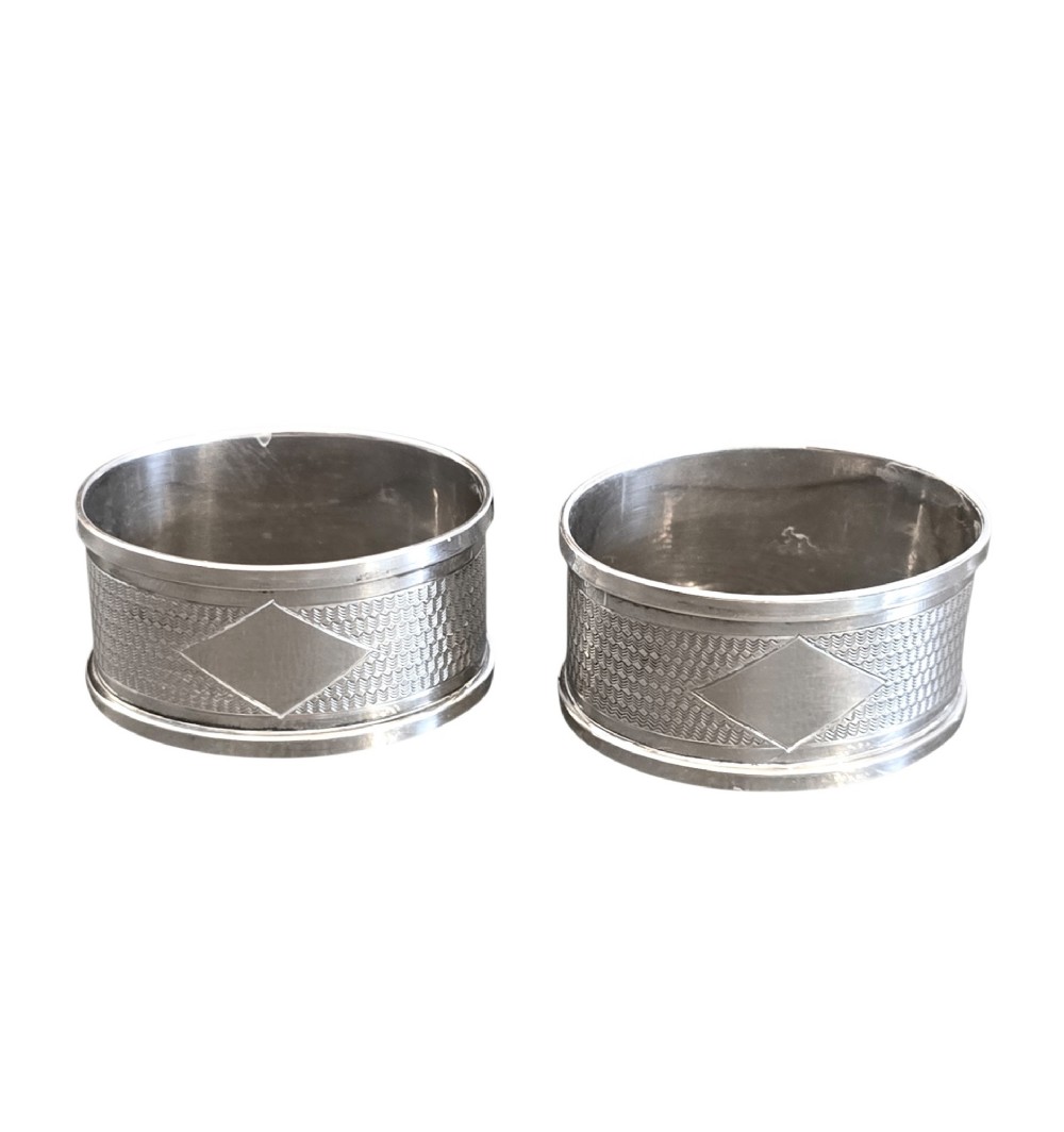 A pair of oval sterling silver napkin rings featuring an engine-turned textured band and plain polished edges. View III