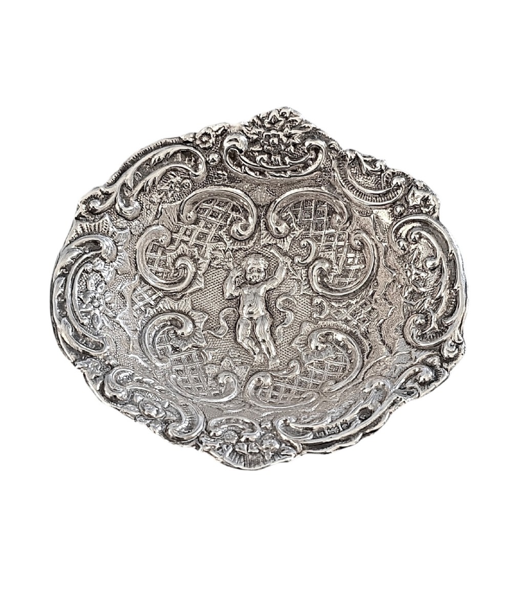 An antique oval sterling silver bonbon dish featuring embossed scrollwork, lattice detailing, a central cherub figure, and spherical ball feet. View III