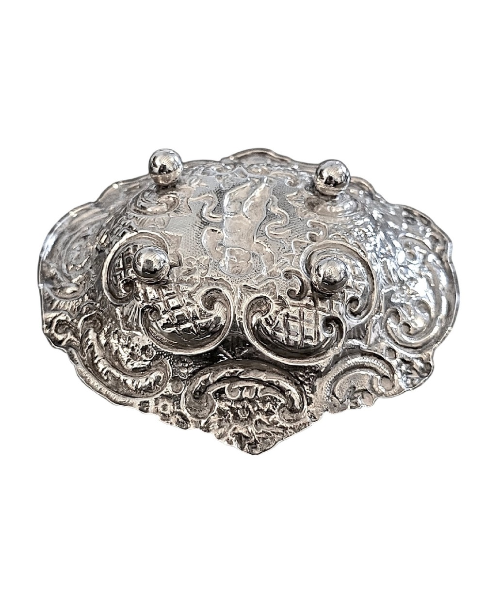 An antique oval sterling silver bonbon dish featuring embossed scrollwork, lattice detailing, a central cherub figure, and spherical ball feet. View IV